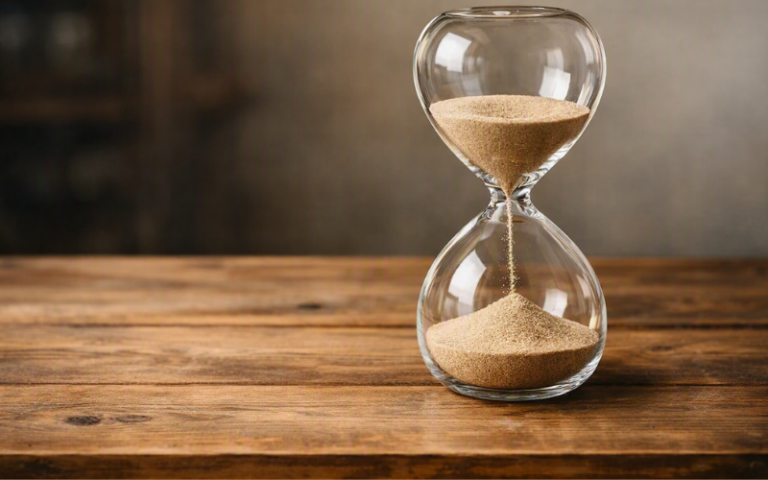 An hourglass resting on a simple wooden table.